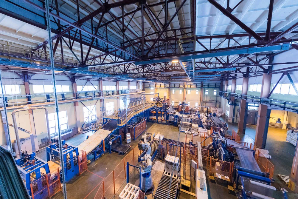 Atelier industriel avec lignes de production, machines automatisées et charpente métallique apparente