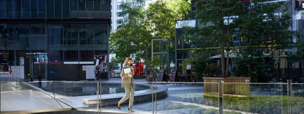 Employée marchant dans un espace extérieur aménagé entre plusieurs immeubles de bureaux