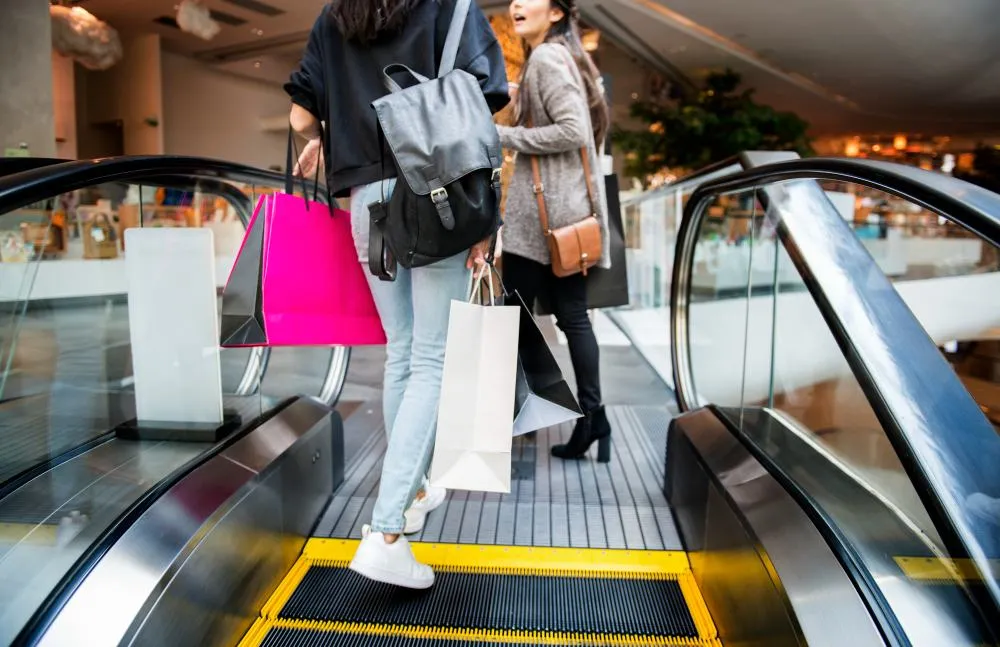 Deux clientes avec des sacs de shopping sur un escalator dans le centre commercial Basso Cambo