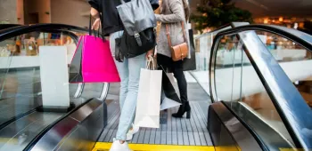 Femmes faisant du shopping Deux clientes avec des sacs de shopping sur un escalator dans le centre commercial Basso Cambo